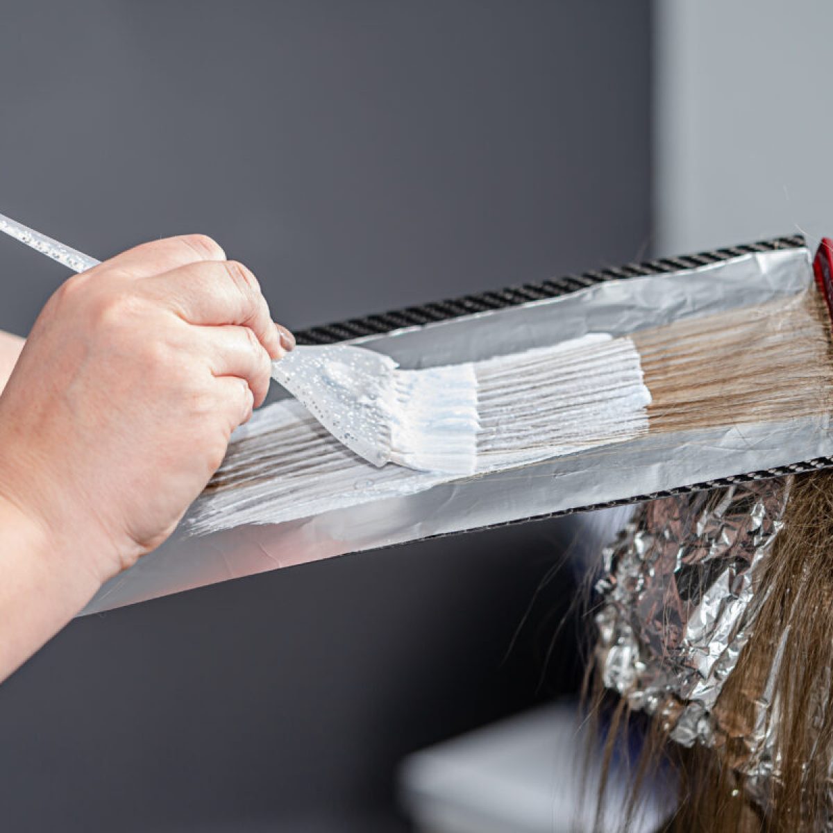 Process of applying bleaching powder on clients hair and wrapping into the foil. Shatush
