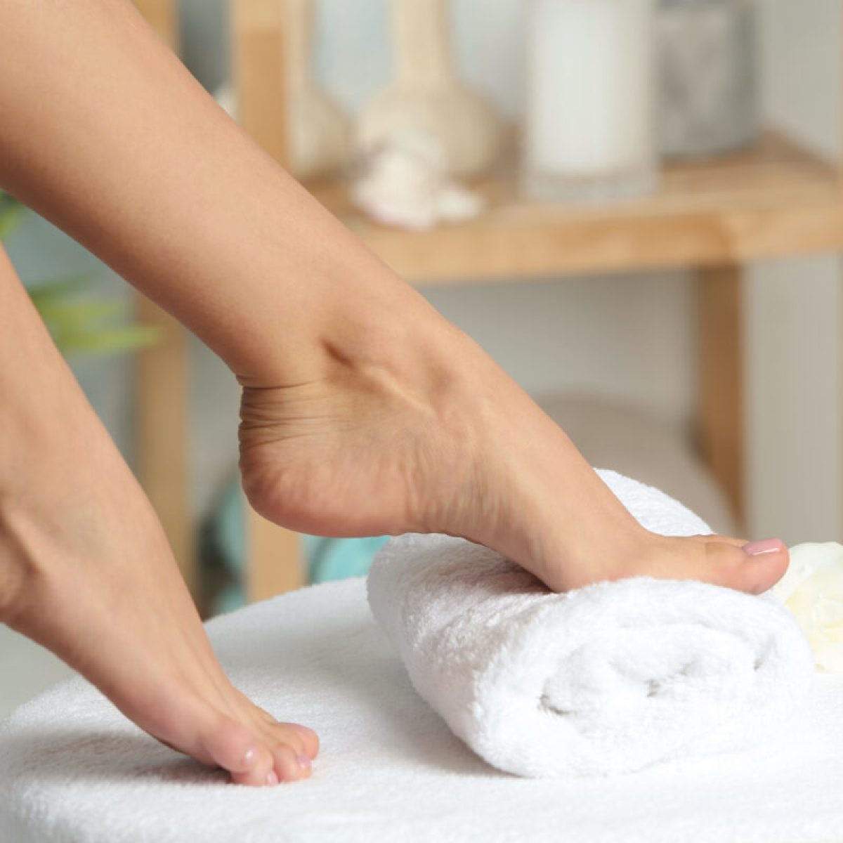 Woman with smooth feet on white towel indoors, closeup. Spa treatment